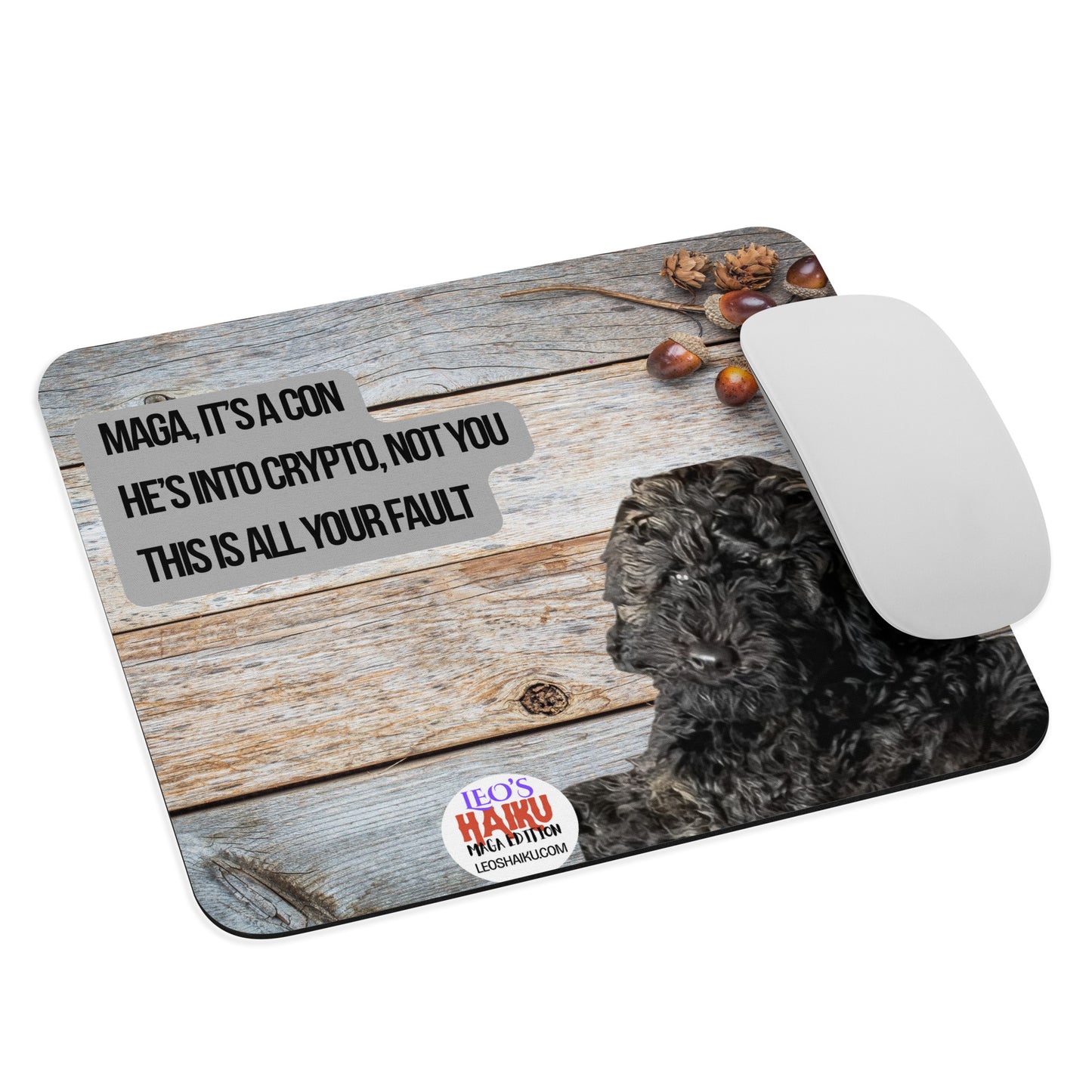 Standard Mouse Pad with an image of Leo the Black Mini Poodle top left against a wooden background. Acorns and pine cones top right with the round text logo for leoshaiku.com below. Centered is a political, satirical, anti-MAGA haiku that reads: MAGA, It's a Con
He's Into Crypto, Not You
This is All Your Fault
A computer mouse sits at the right edge of the pad.