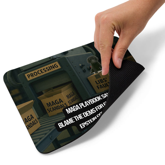 A hand lifts the lower right edge of a Standard Mouse Pad printed with the image of a factory processing line. Open boxes labeled MAGA Scandals go into the processor and come out taped shut and labeled Dems Fault. A black dog sits atop on of the output boxes. A political, satirical, anti-MAGA haiku reads: MAGA Playbook Says
Blame the Dems for Everything
Epstein Coverup!
The text logo for Leoshaiku.com is also displayed. This view shows the thickness of the pad.