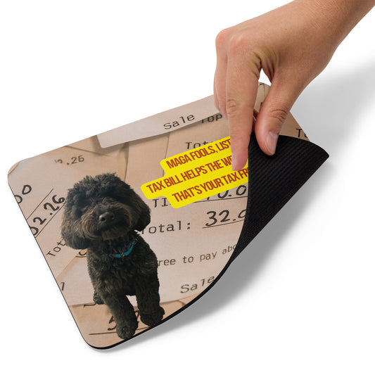 A hand lifts the bottom right edge of a Standard-sized mouse pad printed with the image of a black dog on top of a stack of restaurant receipts showing tips. A political, satirical, anti-MAGA reads: MAGA Fools, Listen
Tax Bill Helps the Wealthy, And
That's Your Tax Free Tip!
The text logo for Leo's Haiku is also displayed. This view shows the thickness of the pad.