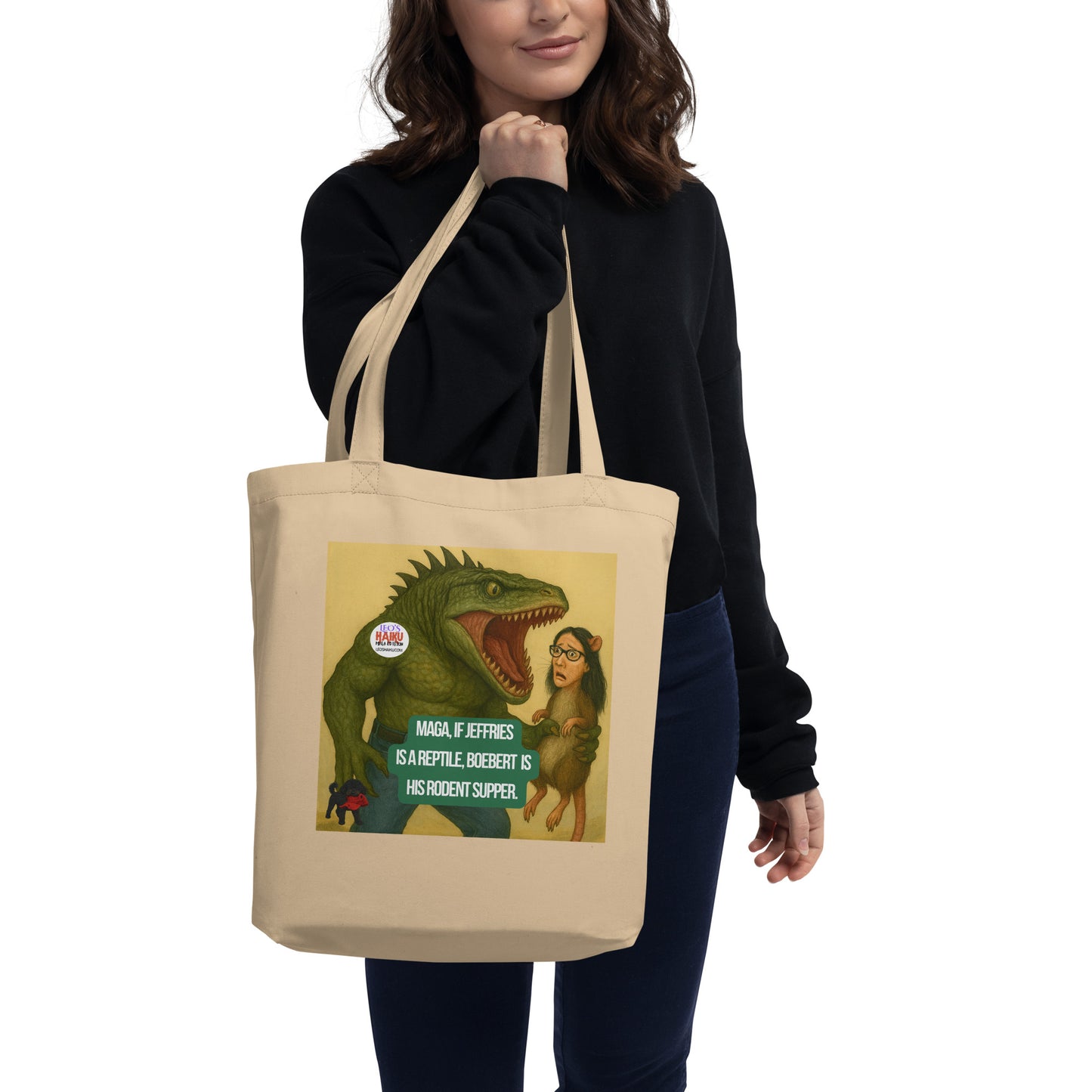Person holding a beige tote bag with a graphic design featuring a half man/half reptile creature preparing to eat a rat with a woman's head.  A satirical, political, anti-MAGA haiku reads:
MAGA, If Jeffries
Is a Reptile, Boebert is
His Rodent Supper.
The circular text logo for leoshaiku.com is upper left.  The image of Leo the black mini poodle with a chewed up red hat in his mouth, is bottom left.