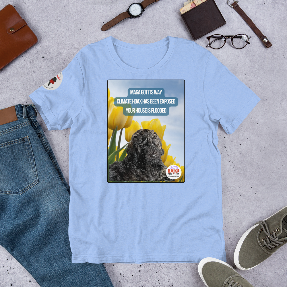 Light blue t-shirt with a graphic design featuring text and an image of Leo the mini poodle.  Shirt is on a gray surface with jeans, shoes, and accessories.  Design on the shirt is Leo in a field of tulips under a blue sky.  A political, satirical, anti-MAGA haiku reads:
MAGA Got Its Way
Climate Hoax Has Been Exposed
Your House Is Flooded
The circular text logo for leoshaiku.com is bottom right.p