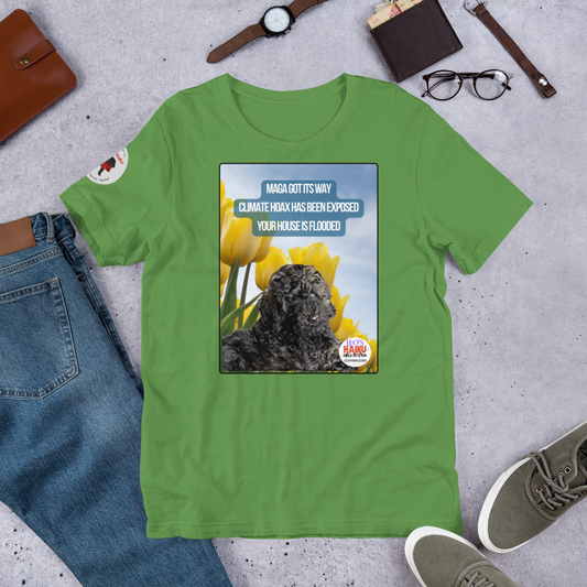 Green t-shirt with a graphic design featuring text and an image of Leo the mini poodle.  Shirt is on a gray surface with jeans, shoes, and accessories.  Design on the shirt is Leo in a field of tulips under a blue sky.  A political, satirical, anti-MAGA haiku reads:
MAGA Got Its Way
Climate Hoax Has Been Exposed
Your House Is Flooded
The circular text logo for leoshaiku.com is bottom right.