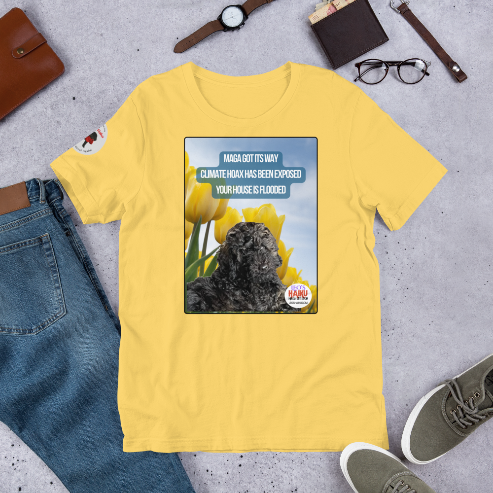 Yellow t-shirt with a graphic design featuring text and an image of Leo the mini poodle.  Shirt is on a gray surface with jeans, shoes, and accessories.  Design on the shirt is Leo in a field of tulips under a blue sky.  A political, satirical, anti-MAGA haiku reads:
MAGA Got Its Way
Climate Hoax Has Been Exposed
Your House Is Flooded
The circular text logo for leoshaiku.com is bottom right.
