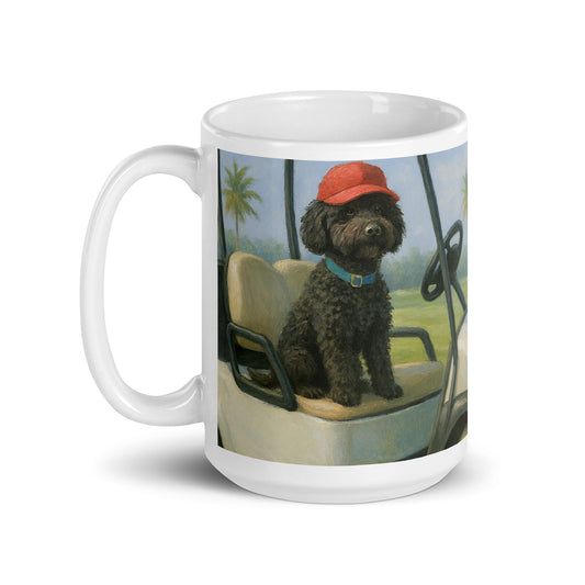 White glossy ceramic mug, handle on the left, printed with image of black dog in a red cap sitting in a golf cart.  Palm trees in the background