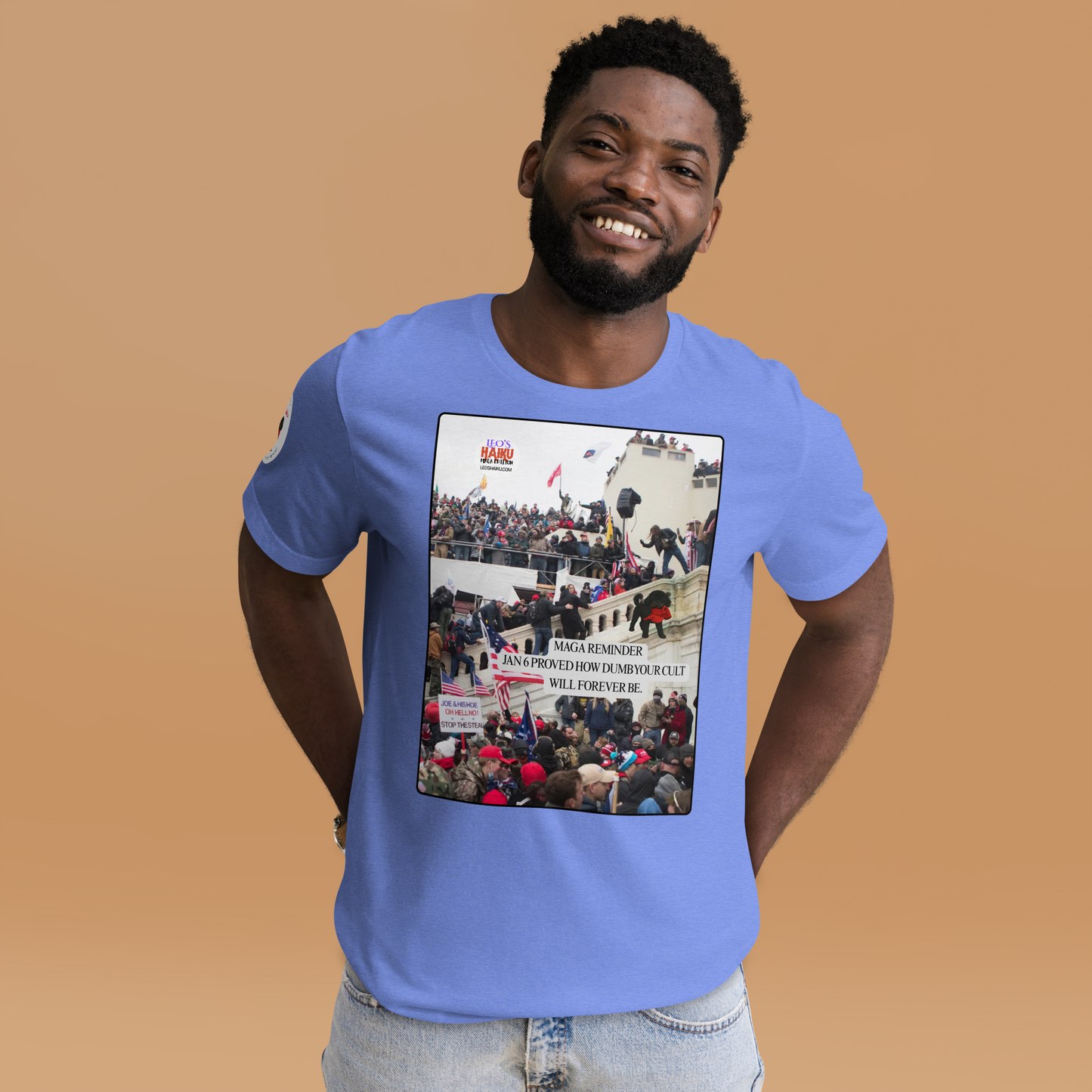 Man wearing a light blue t-shirt with a graphic design showing actual phone of the Jan 6 Insurrection at the US capital.  Leo with a chewed red cap is mid right; the circular text logo of leoshaiku.com is upper left.