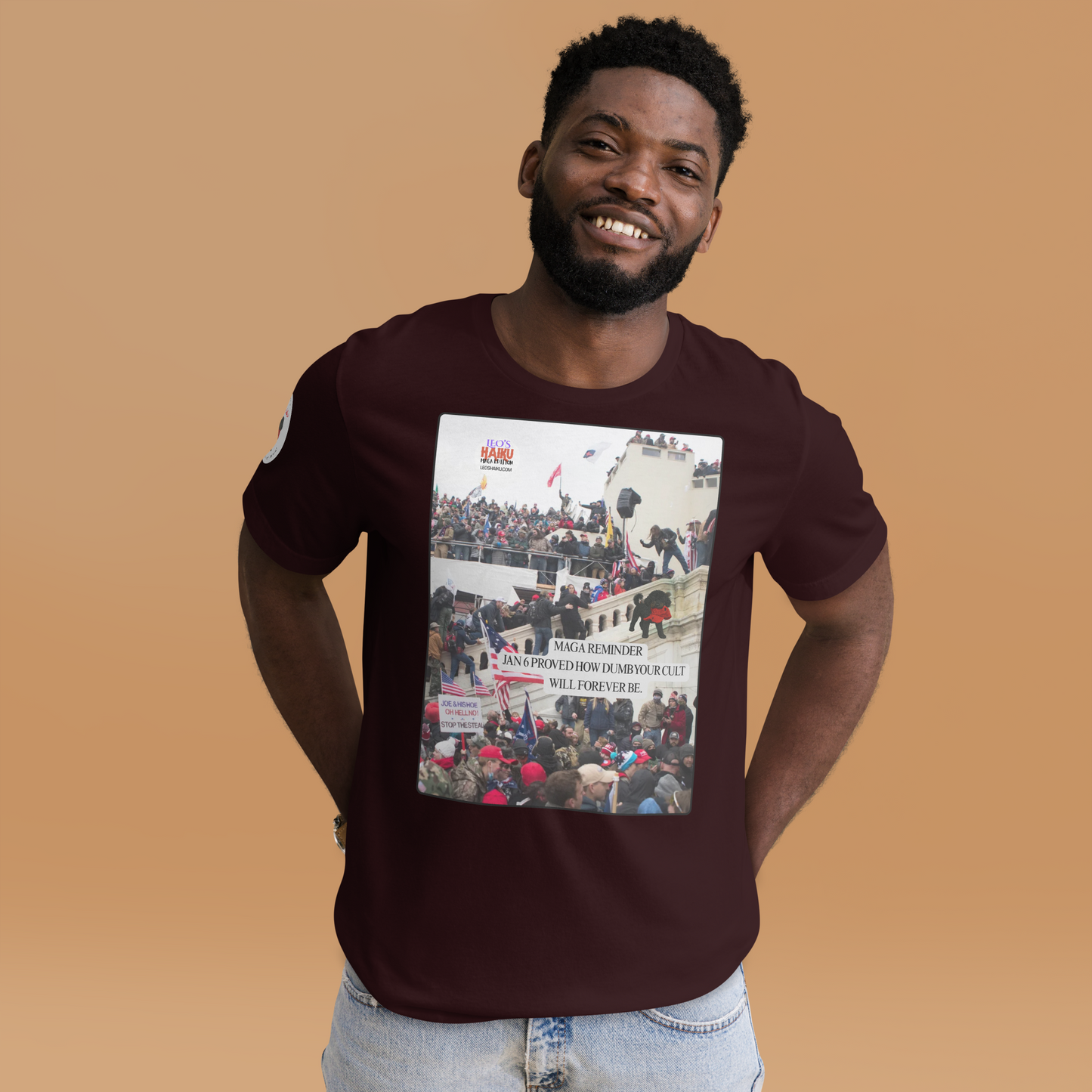 Man wearing a oxblood black t-shirt with a graphic design showing actual phone of the Jan 6 Insurrection at the US capital.  Leo with a chewed red cap is mid right; the circular text logo of leoshaiku.com is upper left.