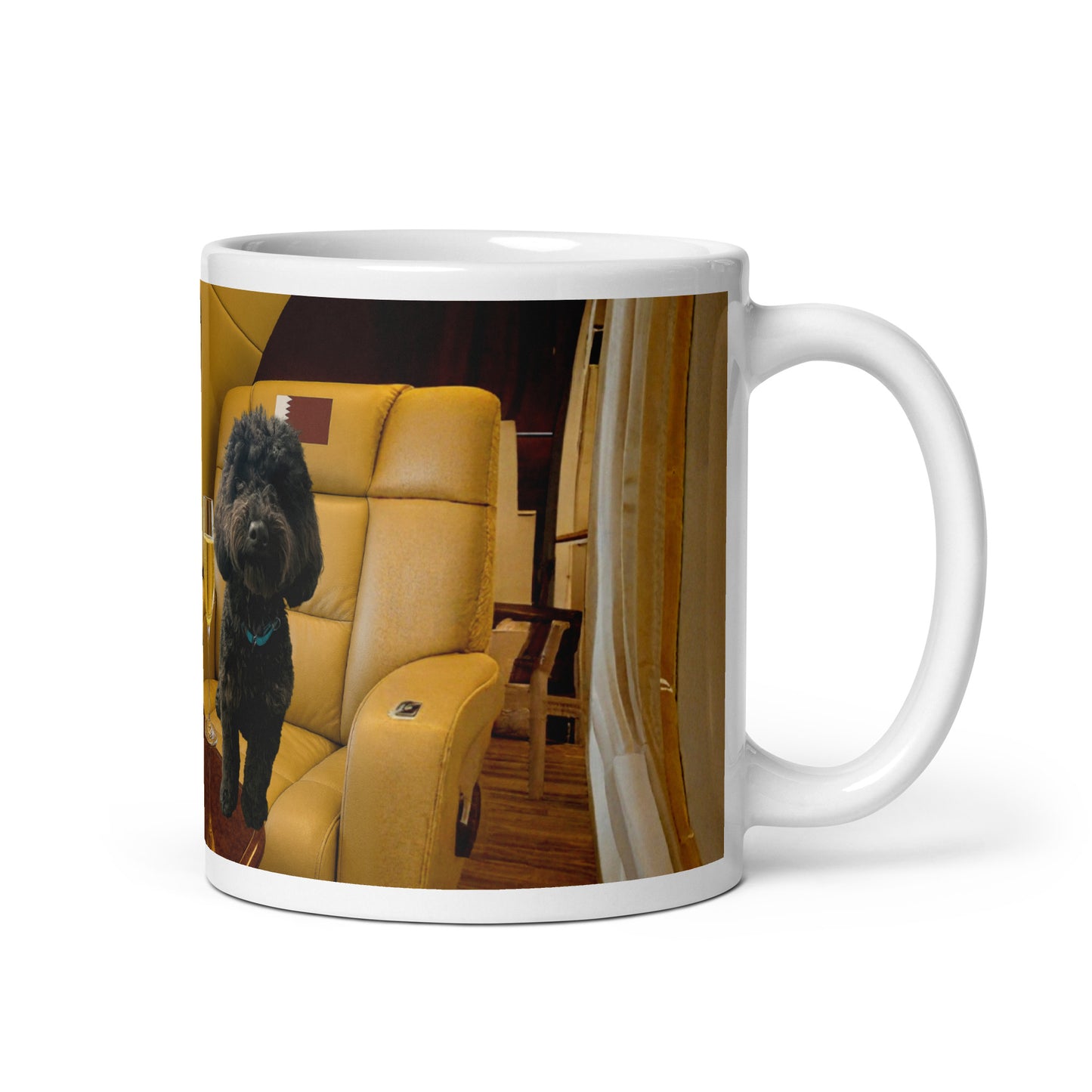 White glossy ceramic mug printed with image of a black dog on a in a leather plane seat with the flag of Qatar in the headrest.