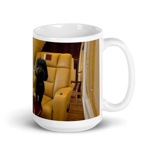 White glossy ceramic mug printed with image of a black dog on a in a leather plane seat with the flag of Qatar in the headrest.