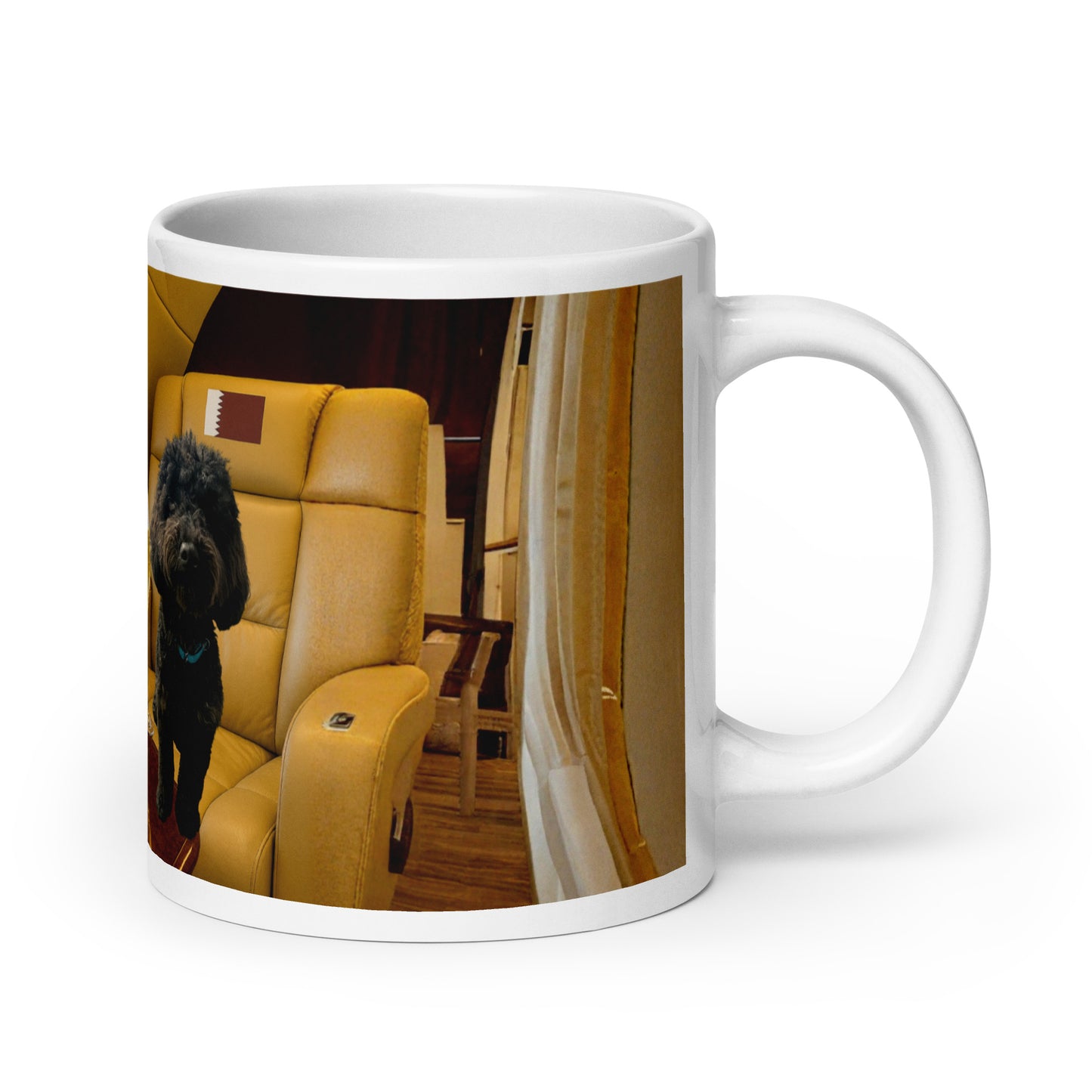 White glossy ceramic mug printed with image of a black dog sitting in the leather seat of luxury jet.  Leather seat has the flag of Qatar in the headrest