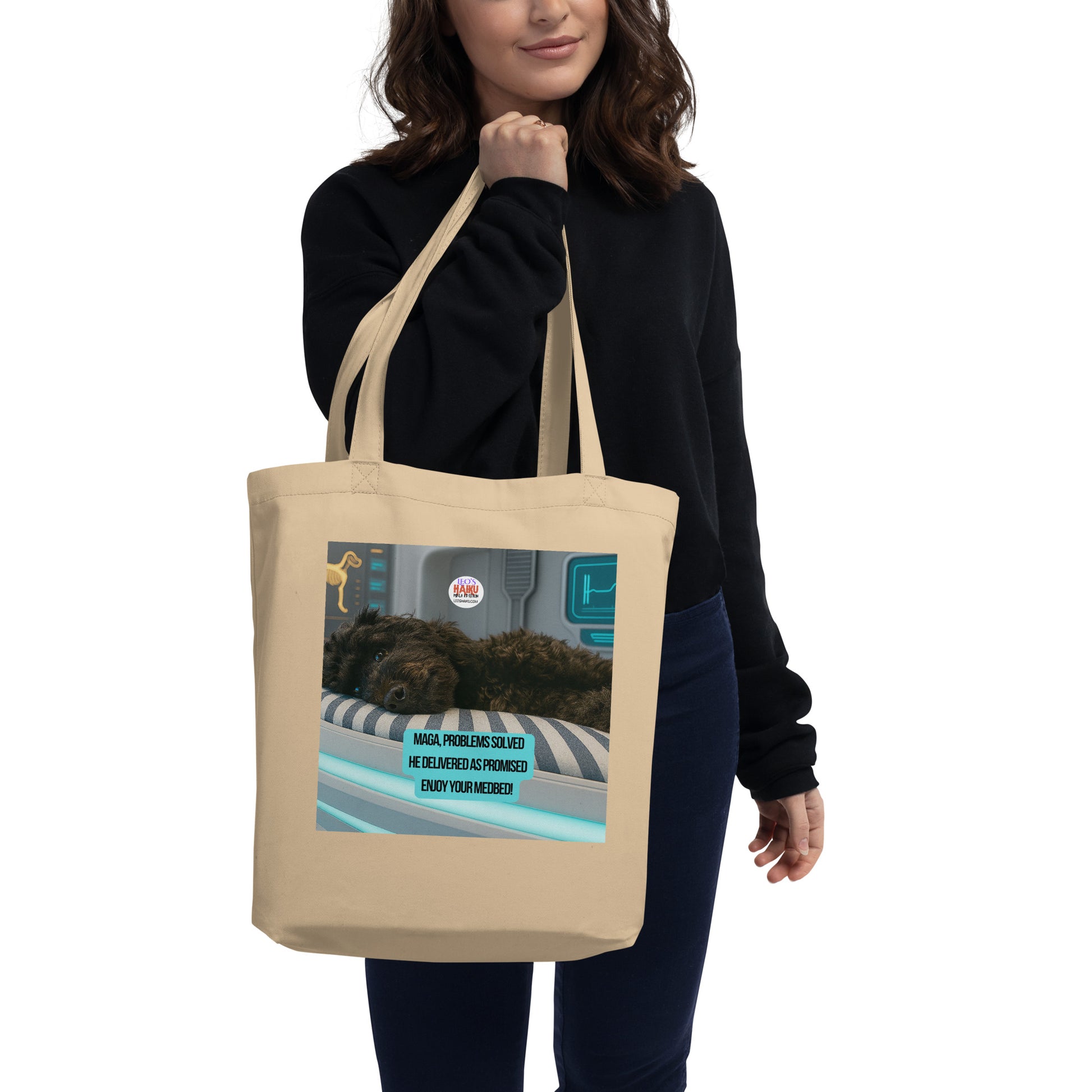 Image of a young woman carrying a beige tote printed with an image of a dog facing the viewer lying on a high tech med bed in a laboratory setting.