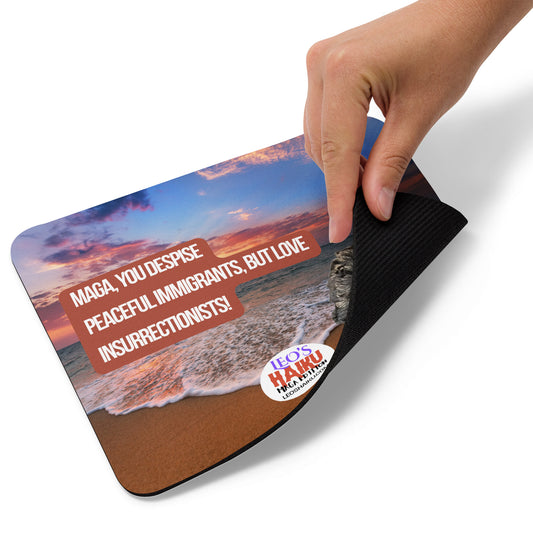 A hand lifts the right bottom corner of a standard mouse pad printed with evening beach scene.  Black poodle bottom right. A political, satirical, anti-MAGA haiku reads:
MAGA, You Despise
Peaceful Immigrants, but Love
Insurrectionists!
The text logo for leoshaiku.com is bottom center.  This view shows the thickness of the pad.