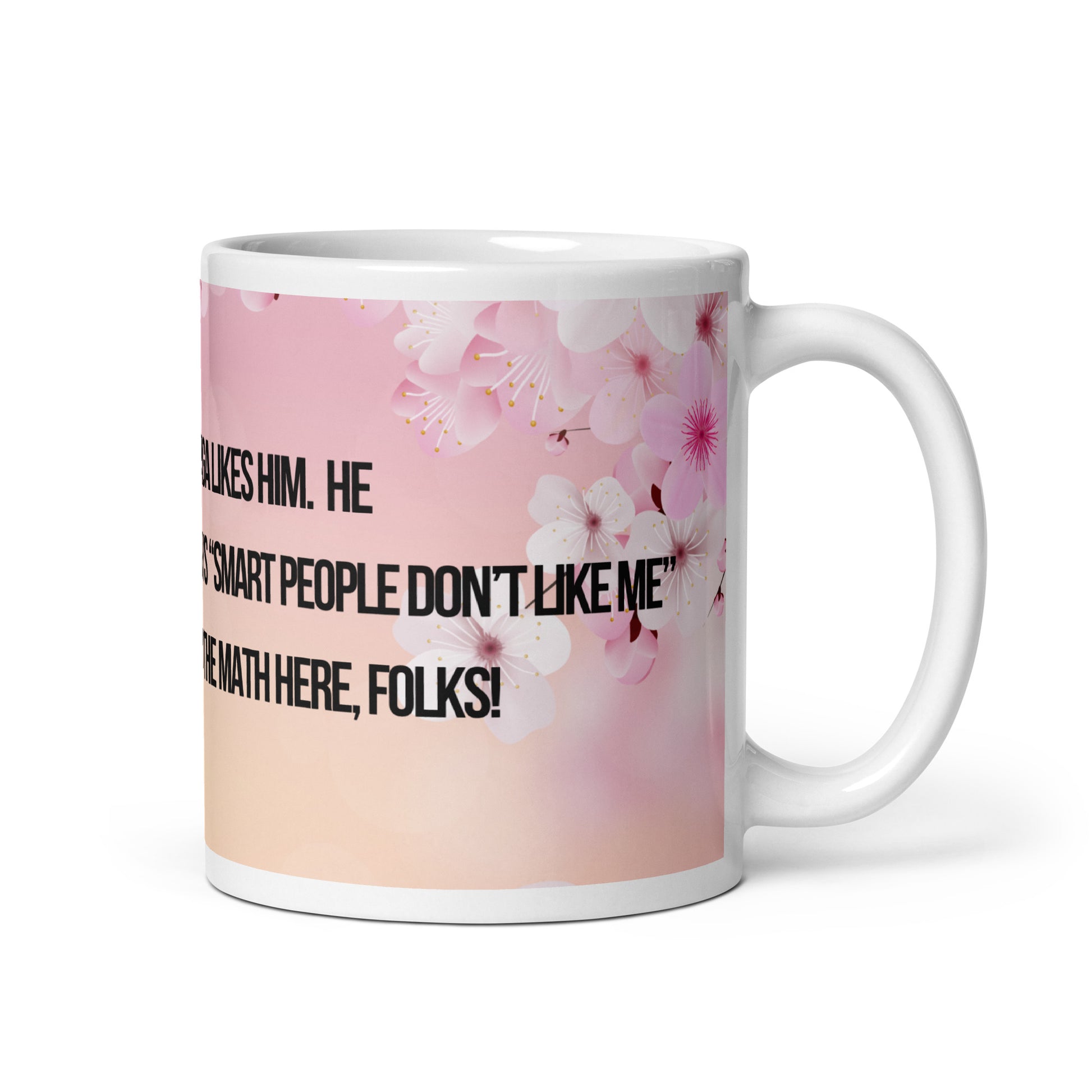 White ceramic mug printed with a pink and white flowered background.  Political, satirical, anti-MAGA haiku is partially visible.