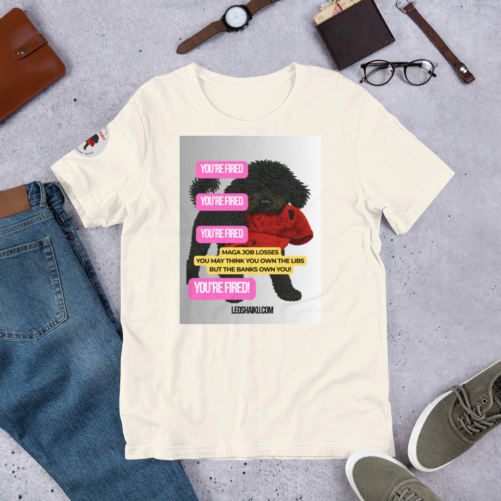 White t-shirt with printed image of Leo the black mini poodle with a chewed red cap in his mouth.  Shirt is surrounded by jeans, watch, glasses, and shoes.  YOU'RE Fired is displayed 4 times in pink.  A political , satirical, anti-MAGA haiku reads:
MAGA Job Losses
You May Think You 0wn the Libs
But the Banks Own You!
Bottom Center it reads "Leoshaiku.com" 