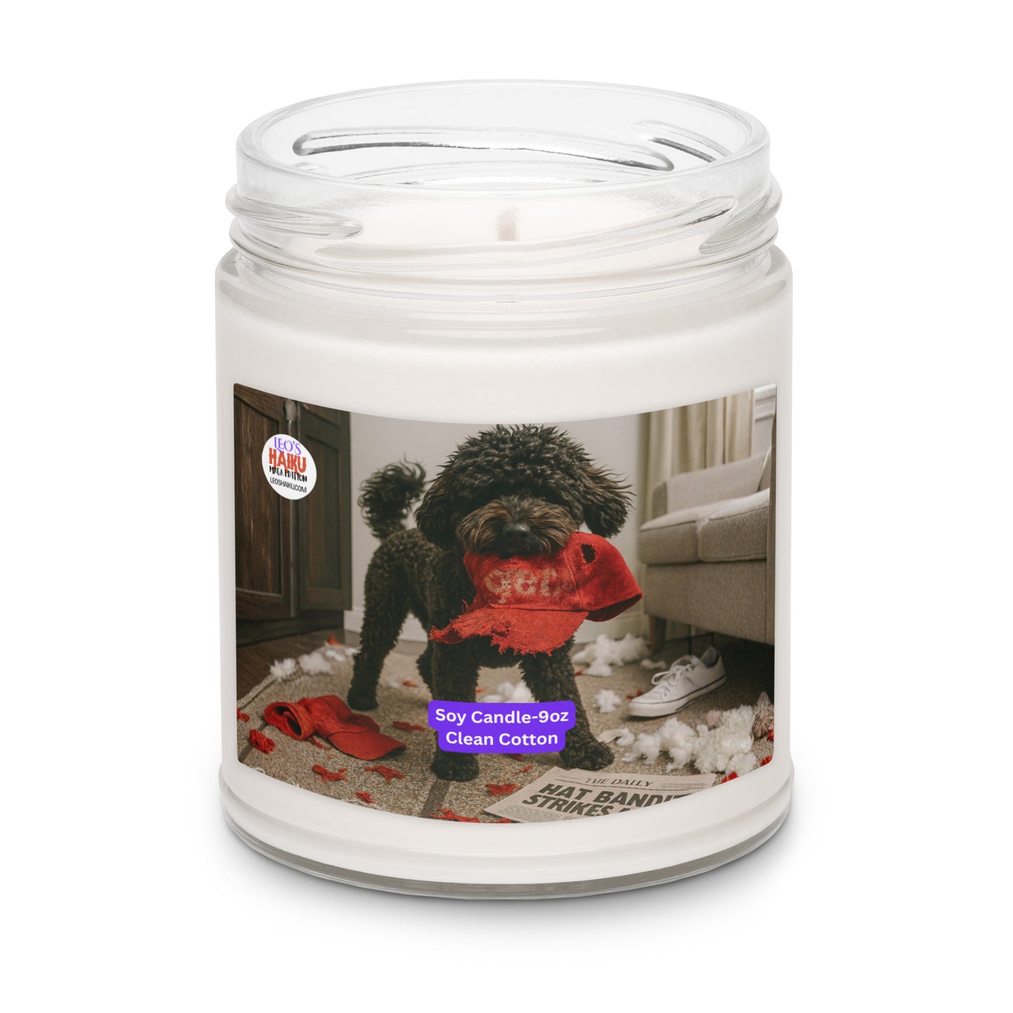 Candle in Glass jar. Label has the picture of a small black dog in the middle of a living room where he has been chewing up things.  He has a chewed red hat in his mouth. To his left is the text logo for leoshaiku.com  Bottom center front is a white text with a purple background that says Soy Candle - 9oz 