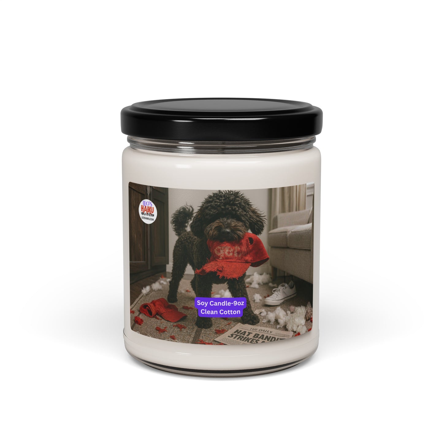 Candle in Glass jar with black metal lid.  Label has the picture of a small black dog in the middle of a living room where he has been chewing up things.  He has a chewed red hat in his mouth. To his left is the text logo for leoshaiku.com  Bottom center front is a white text with a purple background that says Soy Candle - 9oz Clean Cotton