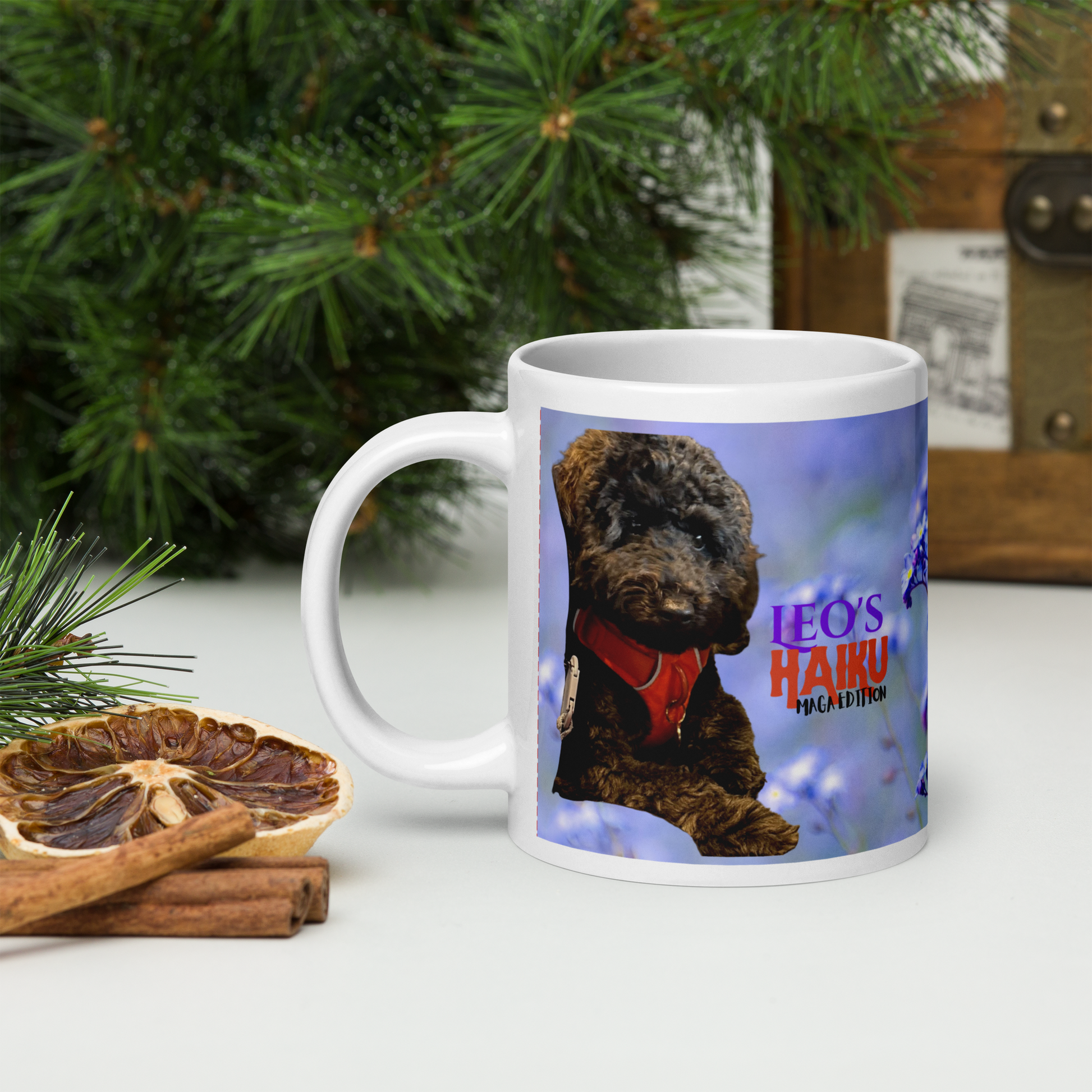 20 oz white ceramic mug printed with blue background, handle on the left and poodle and logo showing. Holiday setting.