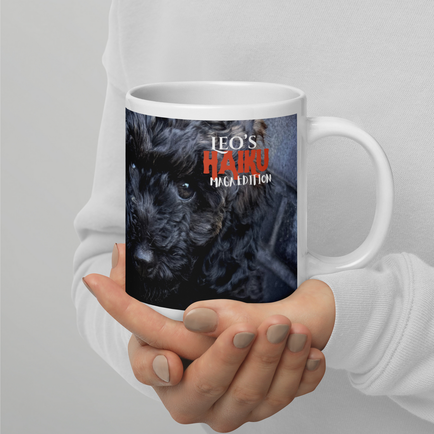 Two hands hold 20 oz white ceramic mug; this view shows the poodle's face and the logo for Leo's Haiku.